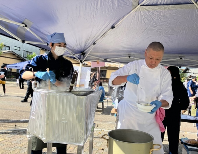 写真:中学生と調理師が屋外で一緒に料理をしている様子